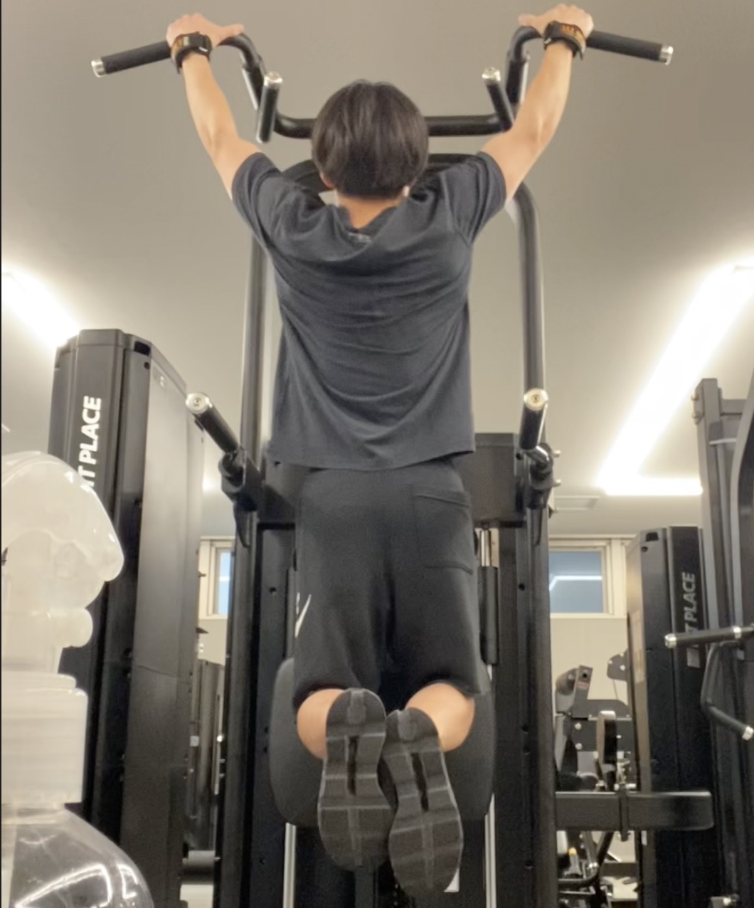 懸垂バーにぶら下がってチンニング（懸垂）をしている様子